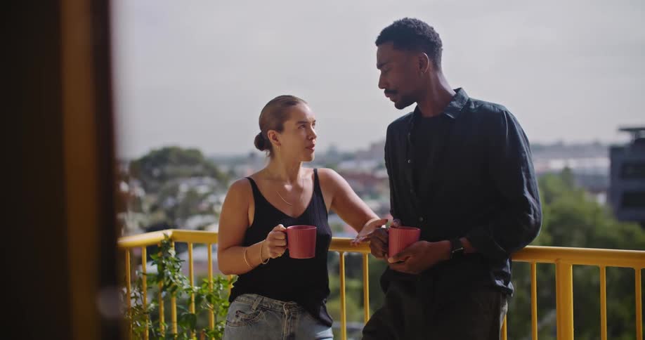 A man and woman have coffee on the balcony