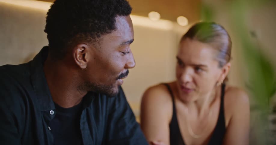 A man and woman chat while looking at a laptop together