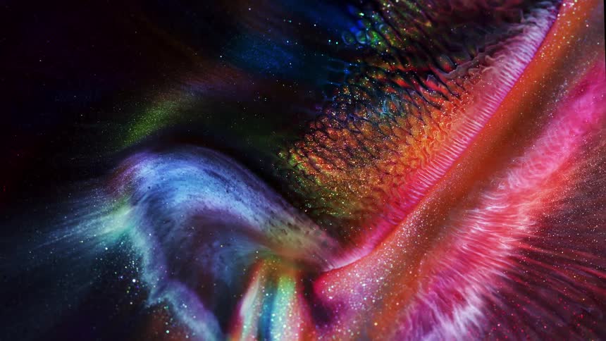 Colorful bright glittering liquid inks flowing over a black background