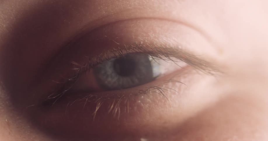 A person with blue eyes slowly blinks