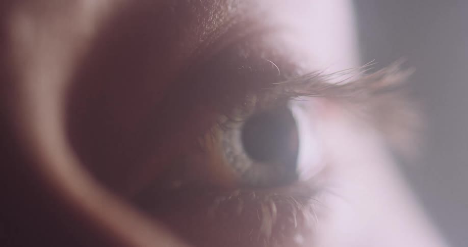 A closeup of a persons eye shows bright light reflecting off of it