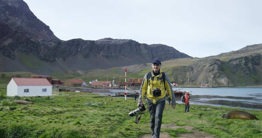 Man carrying his camera as he walks away from the water's edge