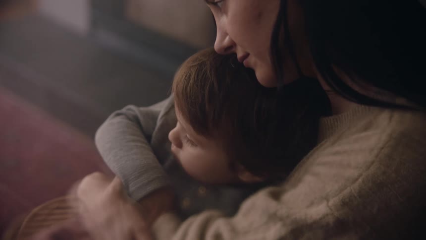 A mother holding her little son quietly rocking him side to side in her arms