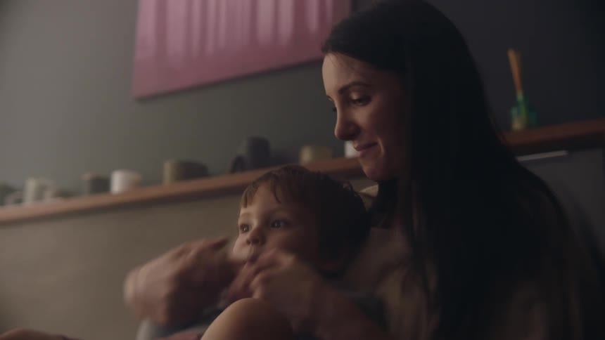 Toddler son sits on mothers lap playing together