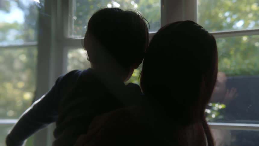 Mother and son look out the windows and being silhouetted against the sky