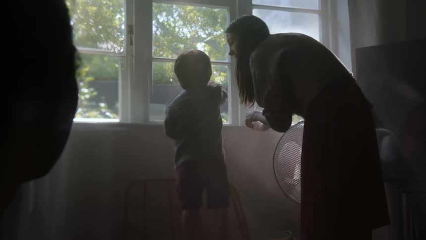 A mother and son are peering out the window