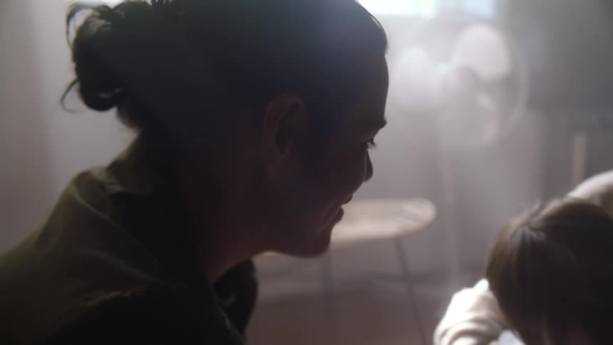 A close up of a womans face as she looks at her son in another persons arms
