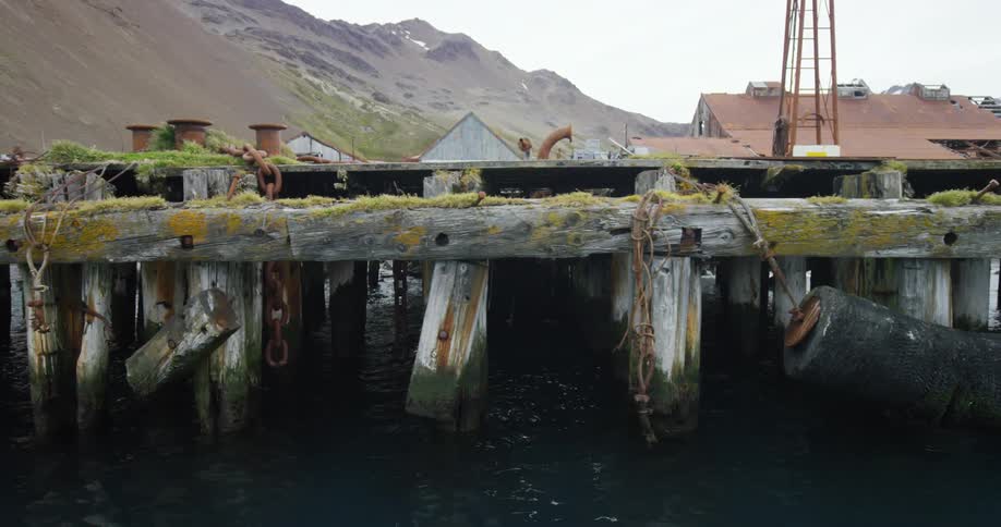 A pier has mountains and houses behind it