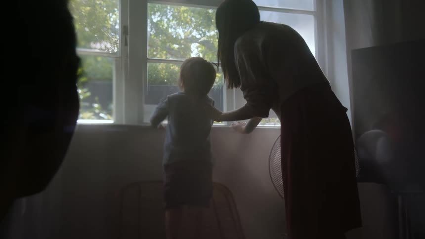 Mother and child are indoors and looking out the window