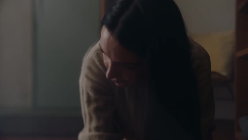 Close up of the face of a woman kneeling on the floor of the living room