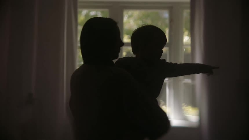 A mother holding her toddler son in her arms as she stands swaying back and forth