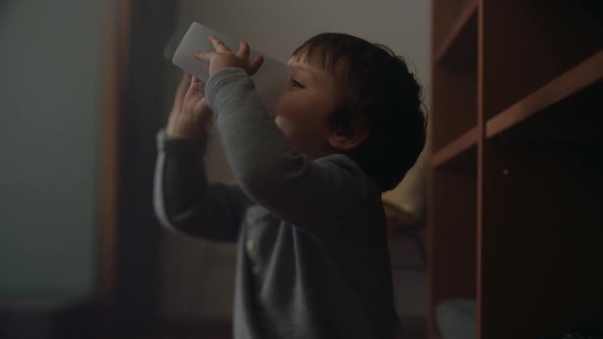 A baby drinking from a cup in a room