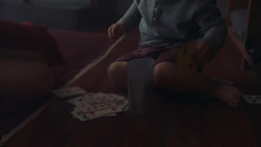 The view is of a toddler that is playing with cards indoors