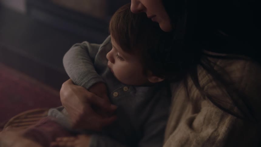 Mother cuddles with her son in the living room at home