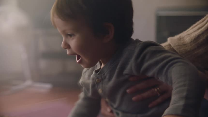A mother who is holding onto her son lets him go slowly as he looks at something that interests him
