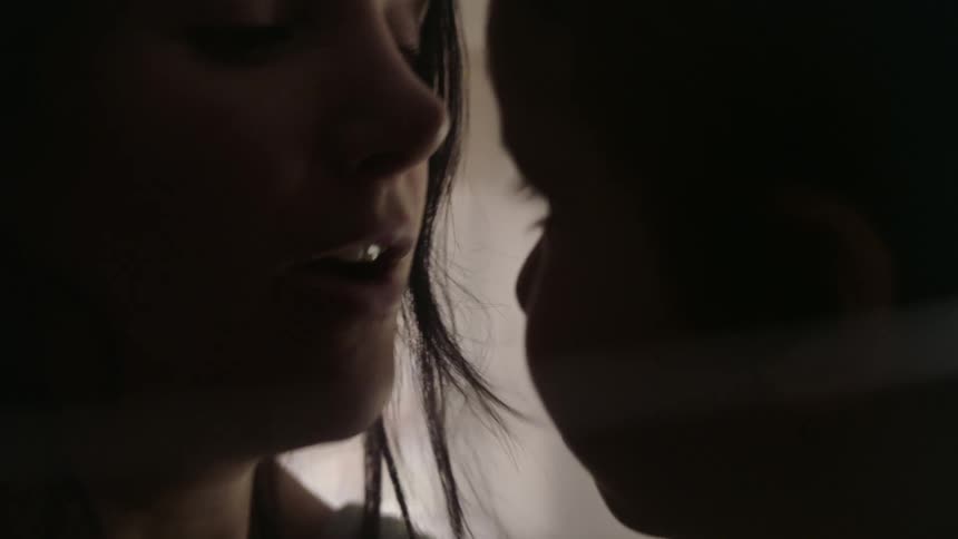 Silhouette of the face of a mother playfully kissing the nose of her baby at home