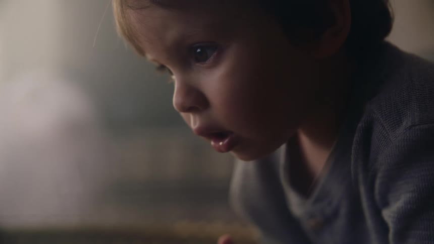 A young boy sits with his mouth open