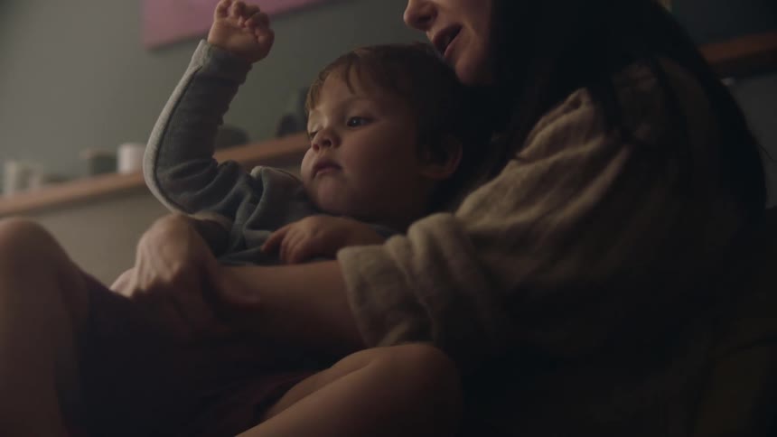 A woman kisses her son on the cheek while he sits on her lap