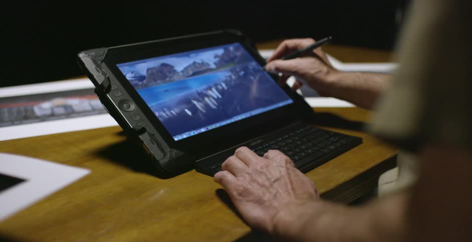 A man uses a pen and tablet to edit a photograph
