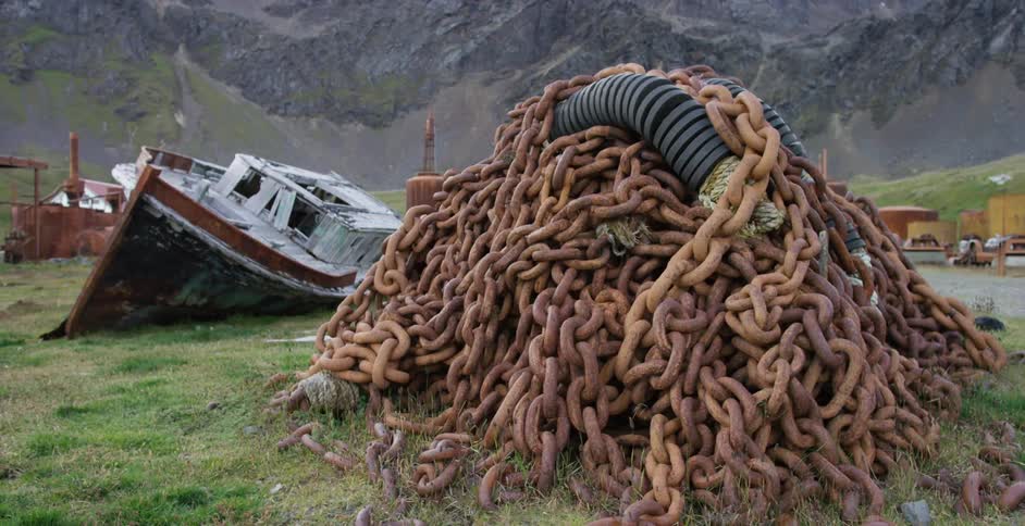 A huge pile of chains is near a boat on the grass