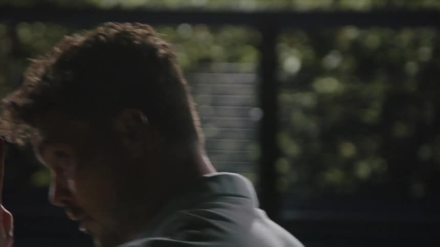 Man with beard and polo shirt plays tennis on court at night
