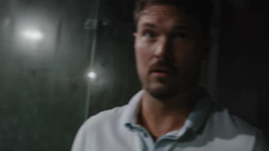 Man with light blue polo shirt plays tennis on the tennis court at night