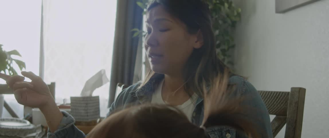 Woman with denim jacket and white shirt sits at table with her daughter