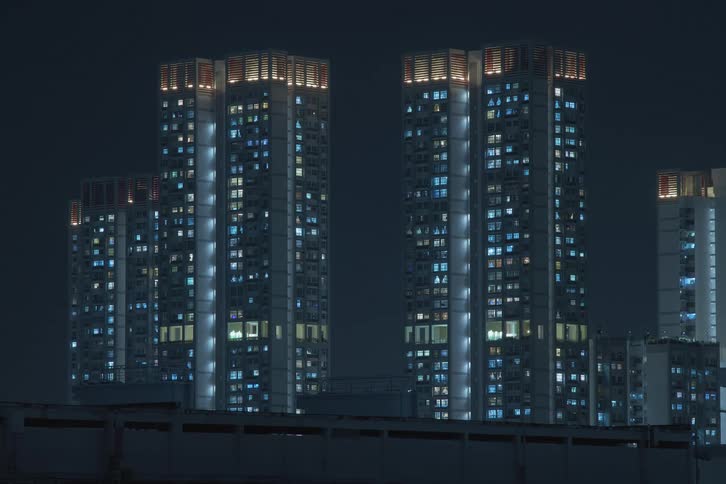 Some highrise building towers are shown with several of blue lights turning on