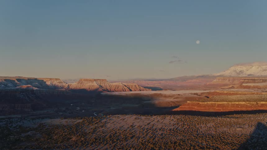 Panoramic aerial view of the full moon over valleys and mountains in the desert in the morning