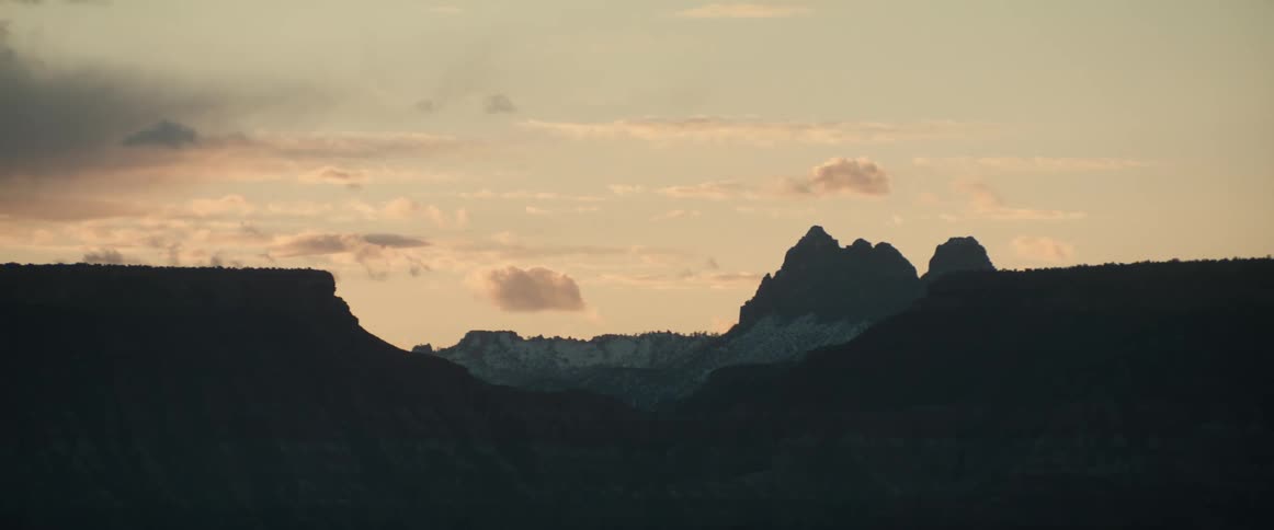 Mountain silhouettes at dusk with desert mesas revealed