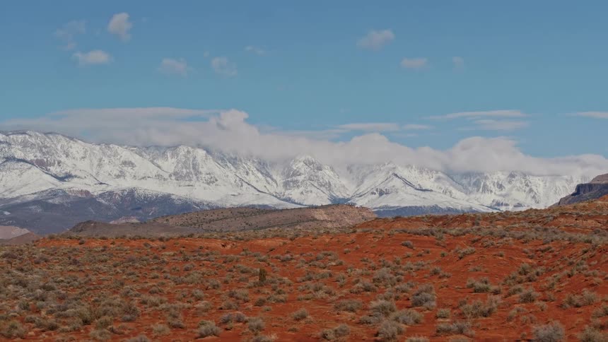 Layers of red desert seen with distant snow covered mountains