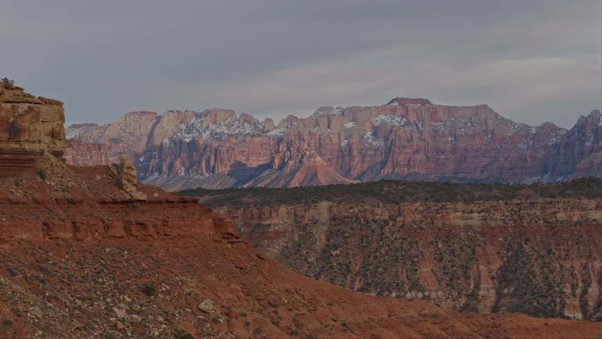 Zion National Park is seen in the distance behind desert mesas and ridges