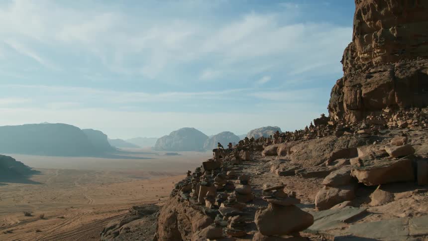 Birds fly over rock covered mountains in the desert badlands under a hazy cloudy sky