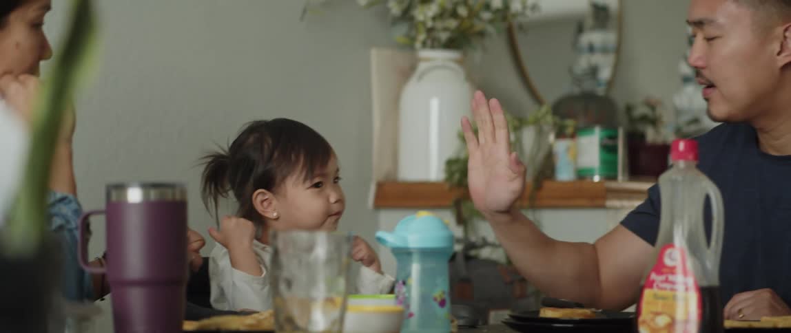 Father and daughter playing with their hands while sitting in the dining room