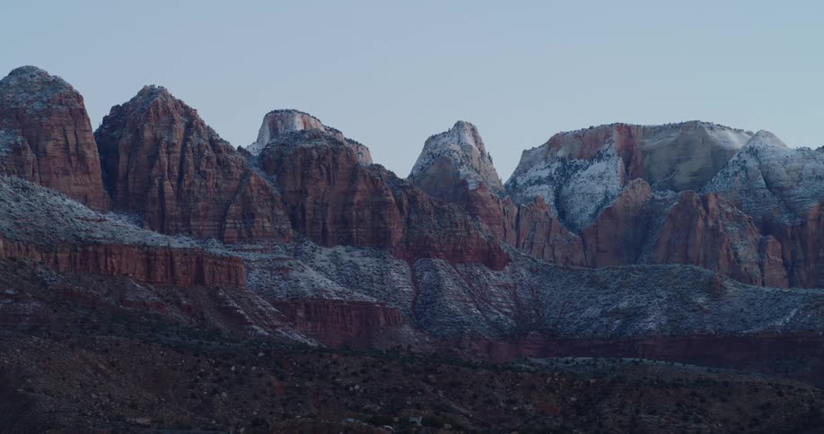Snow covers red rock mountains in the desert