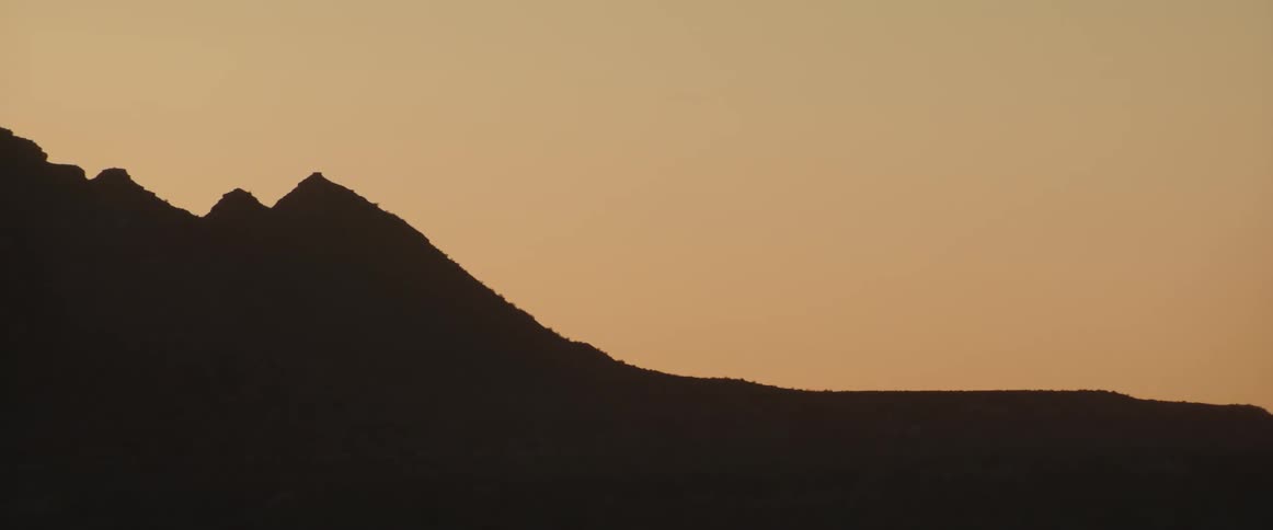 Silhouette of a desert mountain range against the sky in the evening