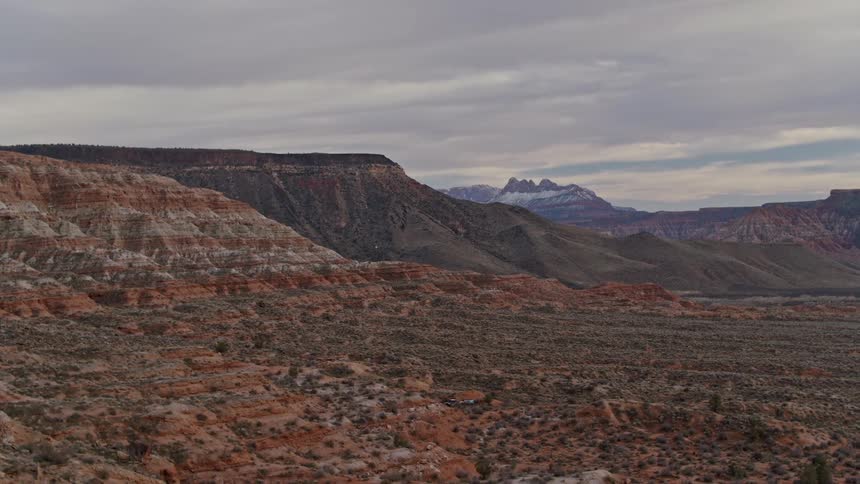 Aerial view of shrubs in the plains next to the mountains in the desert badlands in the evening