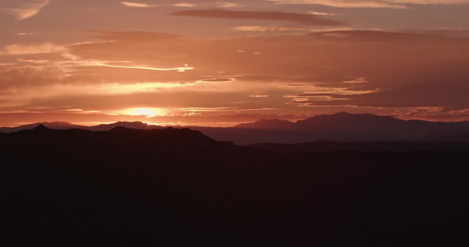The sun sets over an expansive desert mountain range