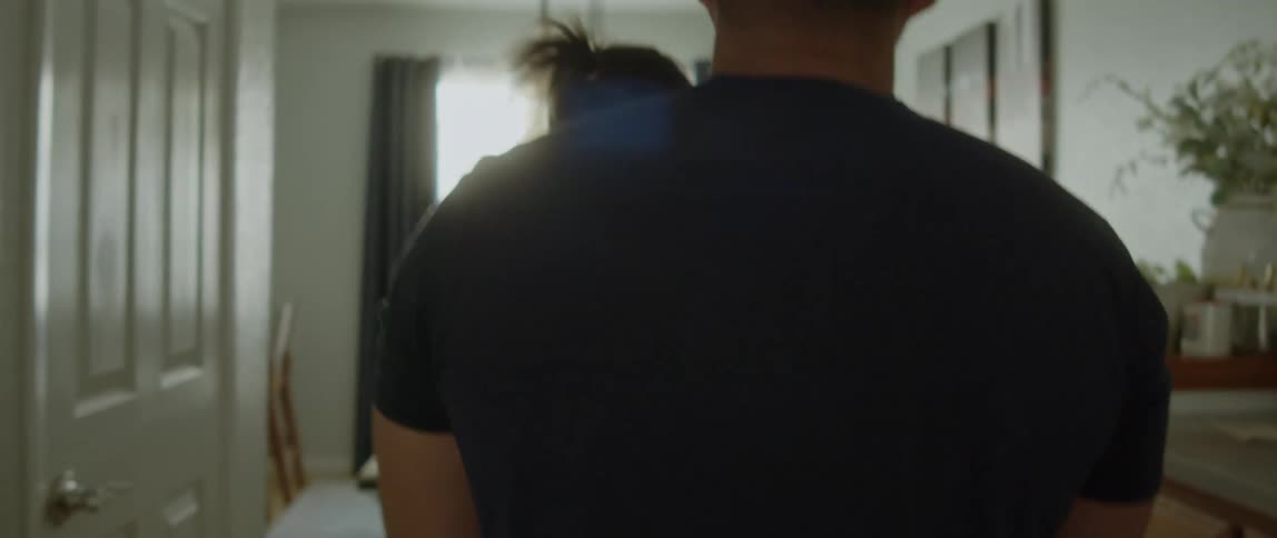 Young father with black t-shirt carries toddler daughter from the living room to the dining table