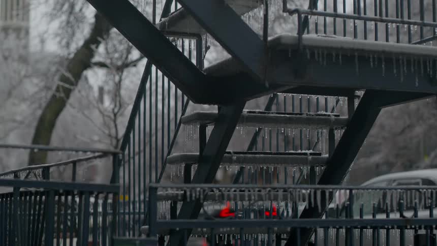 A metal staircase covered in ice in a city during the day