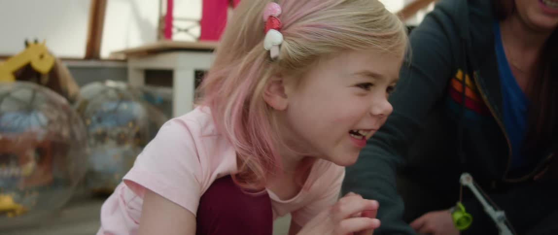 Mother and daughter sit on floor in play room playing with toys