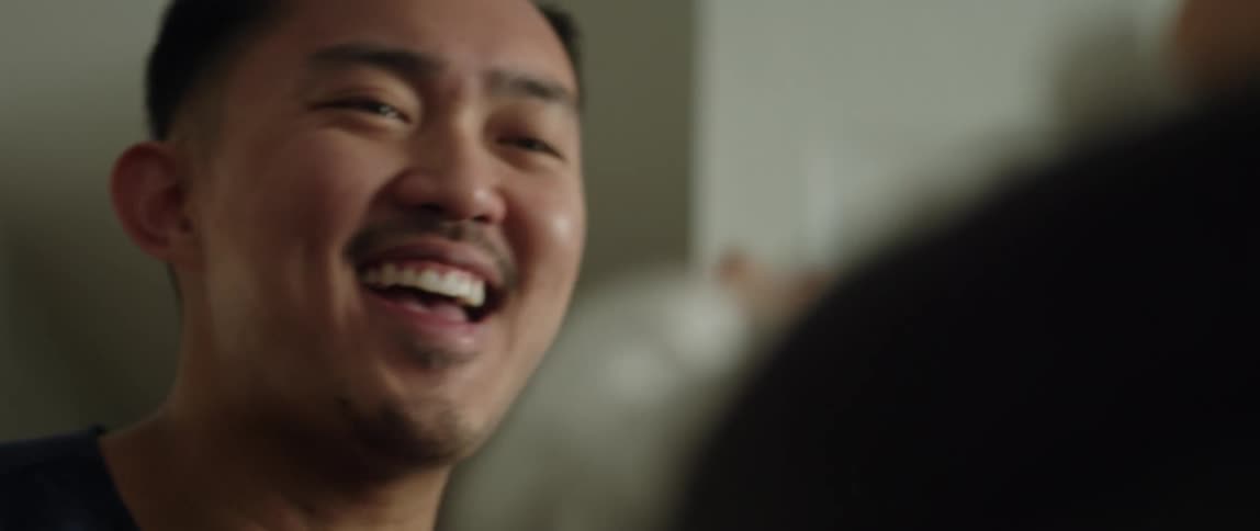A young father smiles as he plays with his infant child through hifives and fist bumps