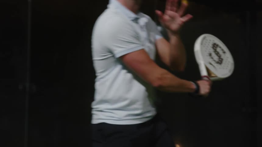 Man playing racquetball in a club swings and hits ball with right hand