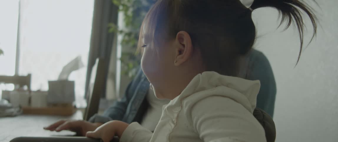 Pregnant mother sits down next to her toddler daughter at the dining table
