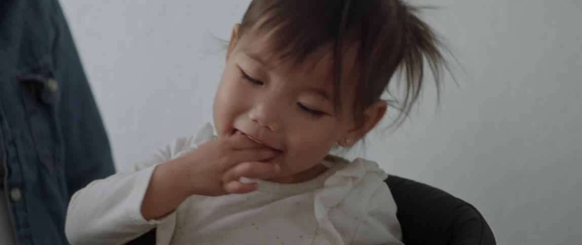 Close up of a girl sitting at the dining room eating food with her fingers