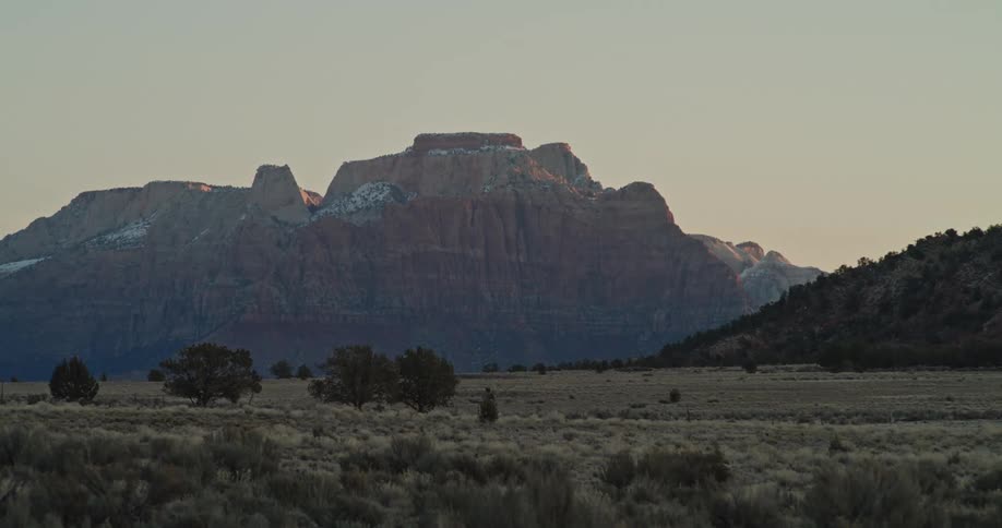 Red rock spires loom over desert brush at dawn