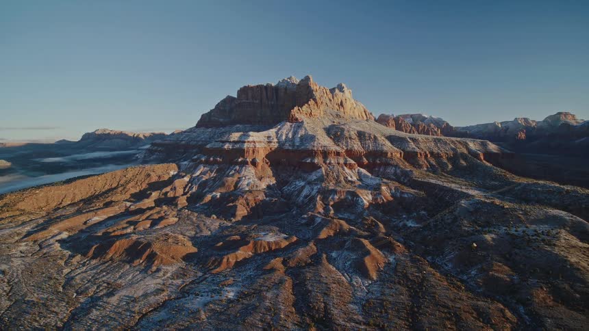 Aerial view of an impressive red rock mountain with a light snow dusting at dawn