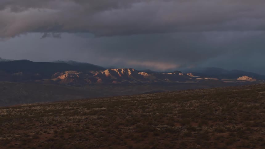 Aerial view of sun lighting distant mountains under stormy skies