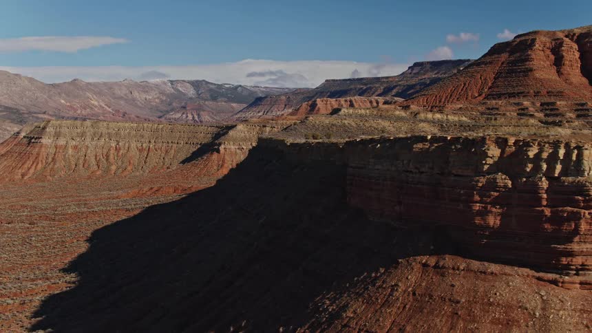 Aerial view as the sun shines brightly upon red rock mesas and mountains