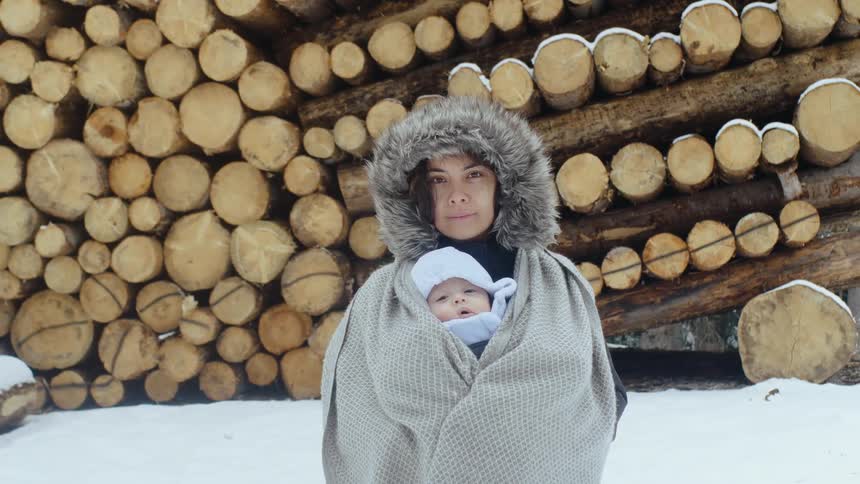 A portrait of mother and baby who are outdoors in the forest during winter time